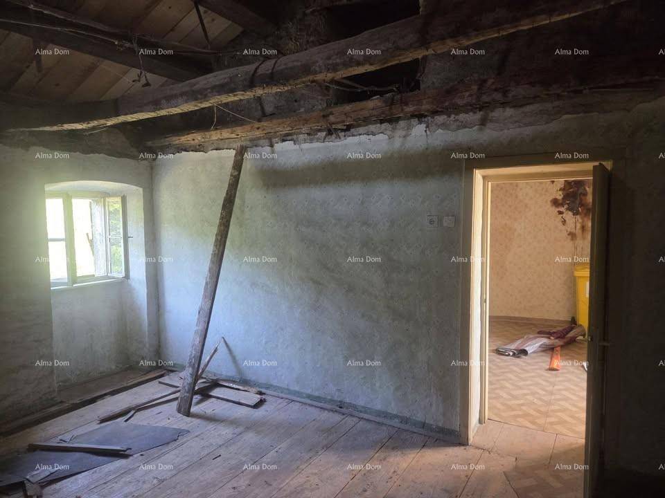 Alter Raum mit sichtbaren Holzbalken, unebenen Wänden und einem Fenster, das viel Licht hereinlässt.