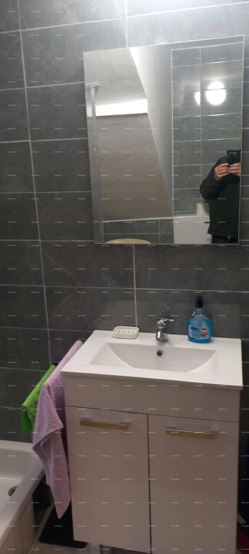 Modernes Badezimmer mit grauen Fliesen, Einzelwaschbecken und großem Spiegel.