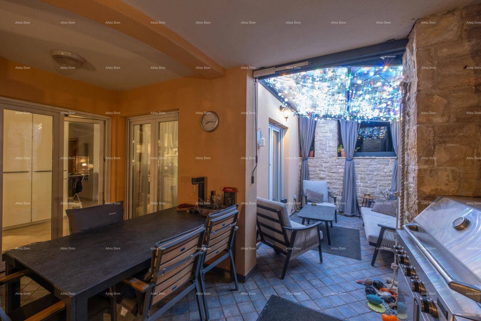 Überdachte Außenterrasse mit Essbereich, Grillstation und Lichterketten für Abendstimmung.
