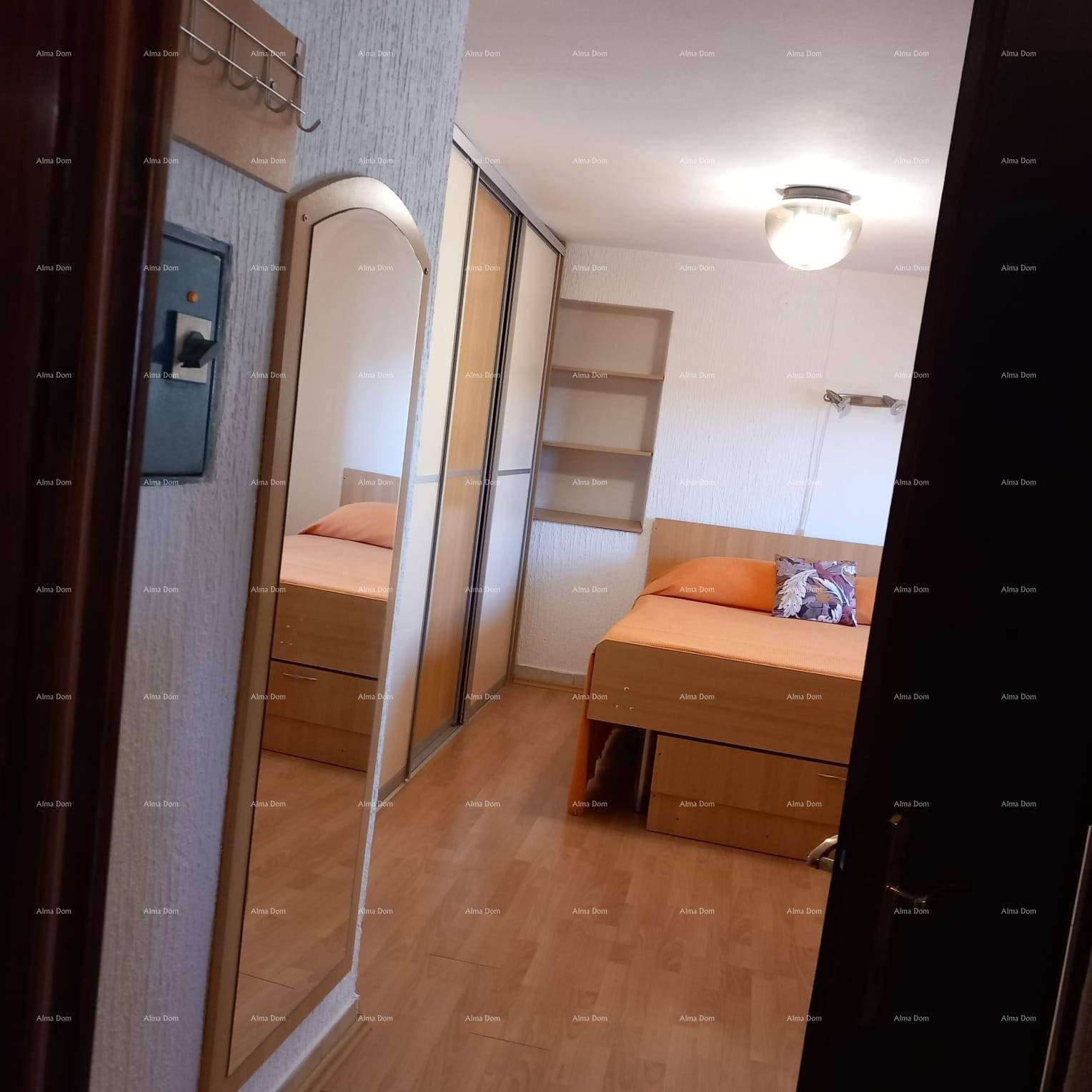 Schlafzimmer mit Holzbett, Spiegeltür und Laminatboden, hell und funktional.