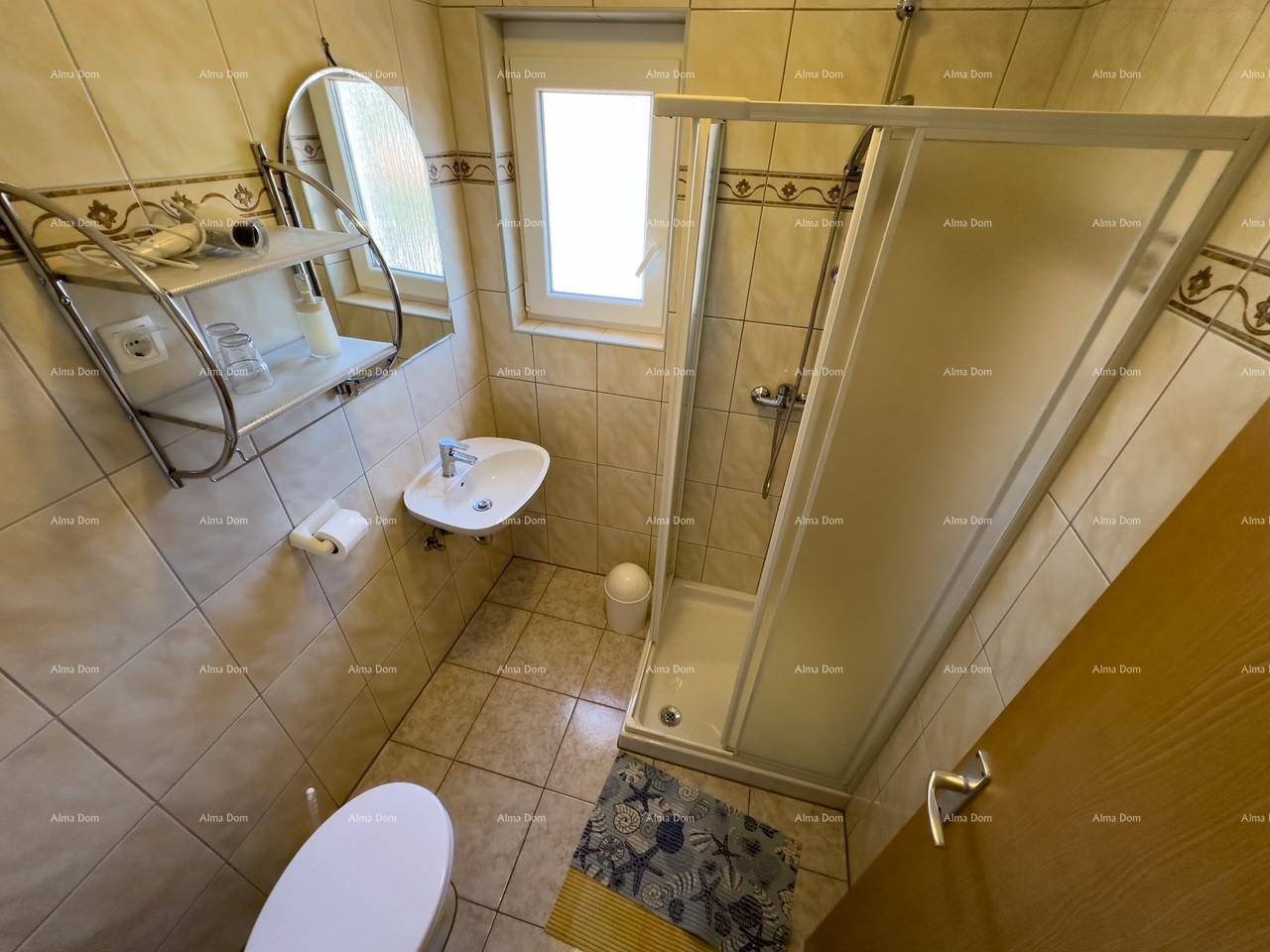 Funktionales Badezimmer mit Duschkabine, WC und Waschbecken in neutralen Fliesenfarben.