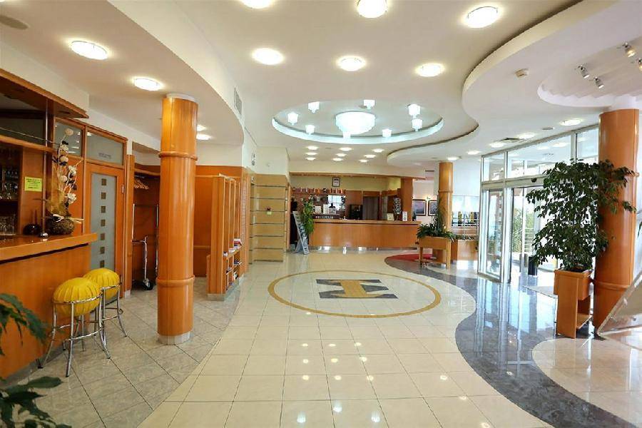 Geräumige und helle Hotellobby mit Rezeption, Sitzgelegenheiten und dekorativem Fliesenboden.