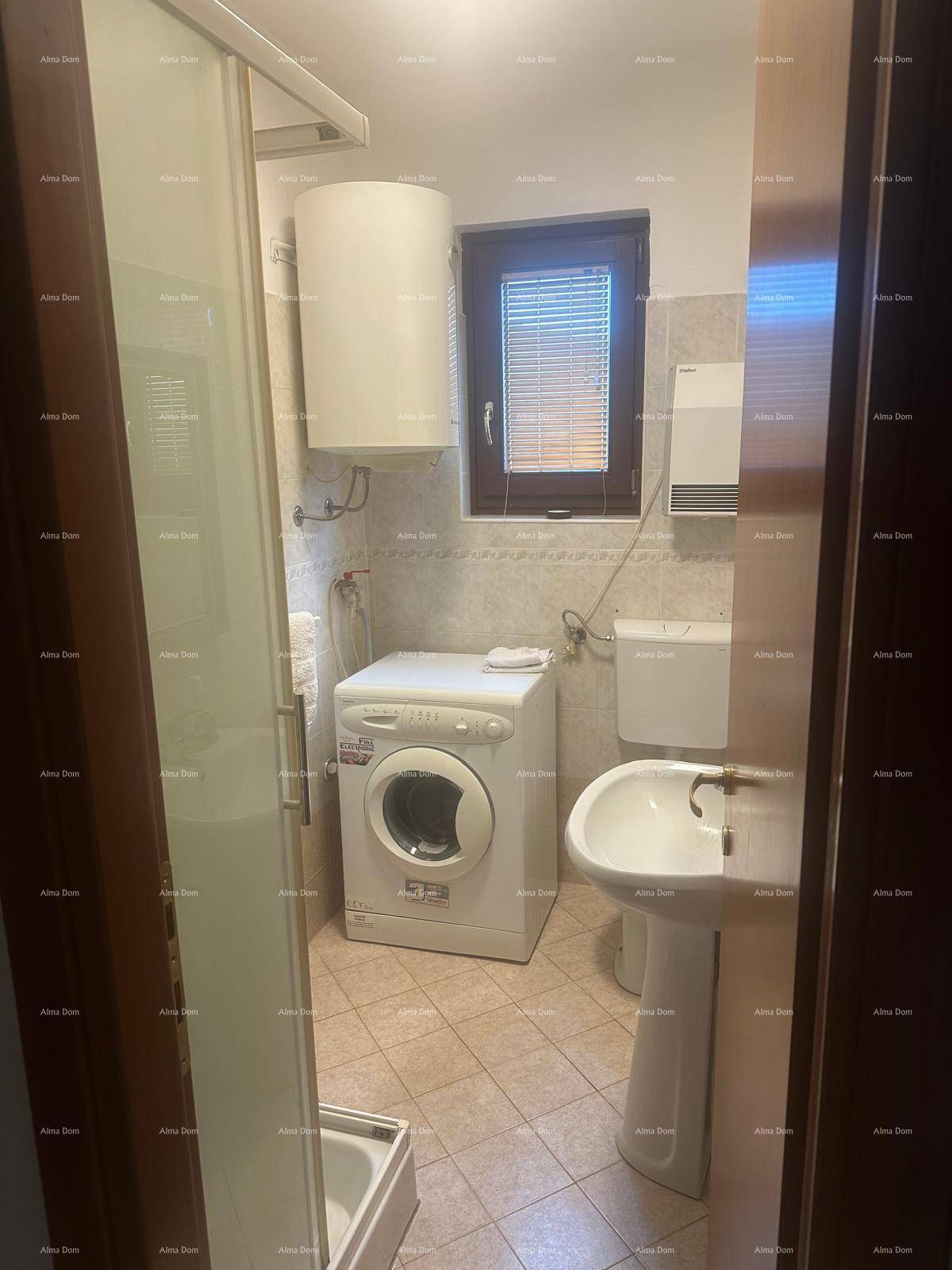 Funktionales Badezimmer mit Duschkabine, Waschmaschine und Fenster mit Jalousien.