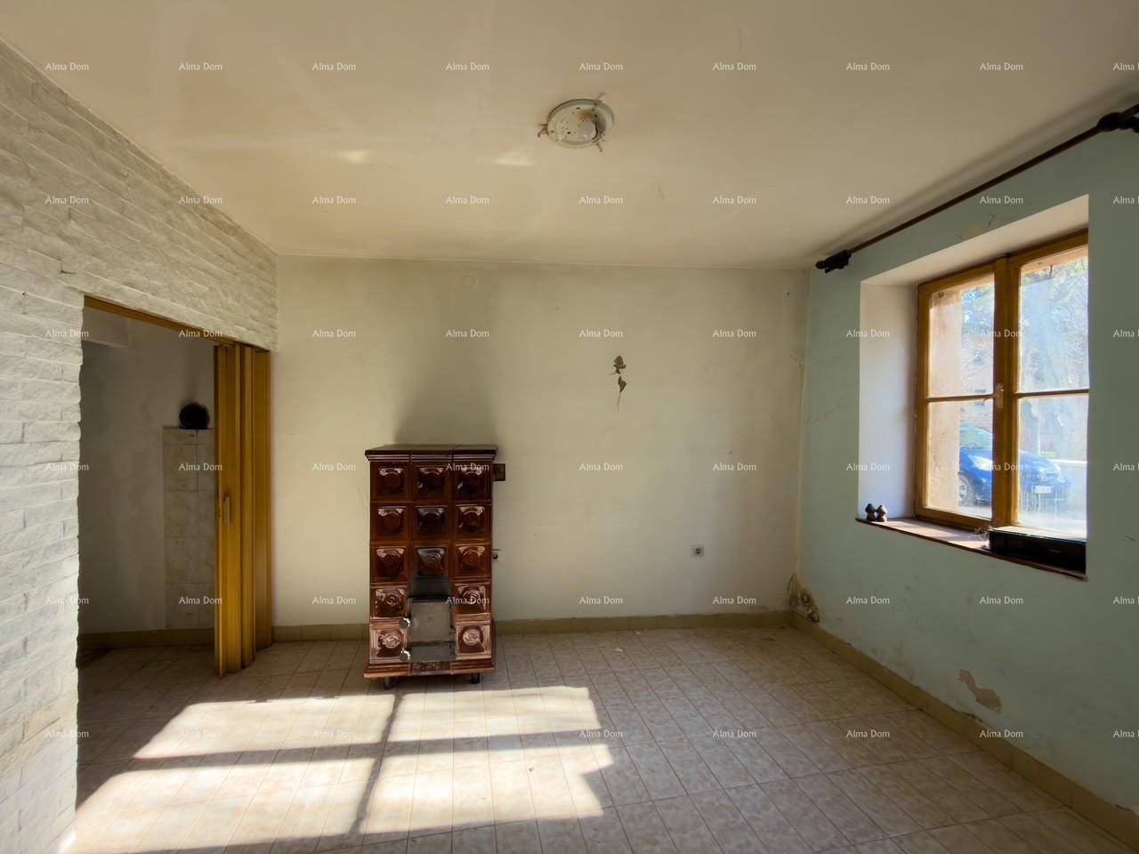 Geräumiger Raum mit einem traditionellen Kachelofen, Fliesenboden und einem Fenster.