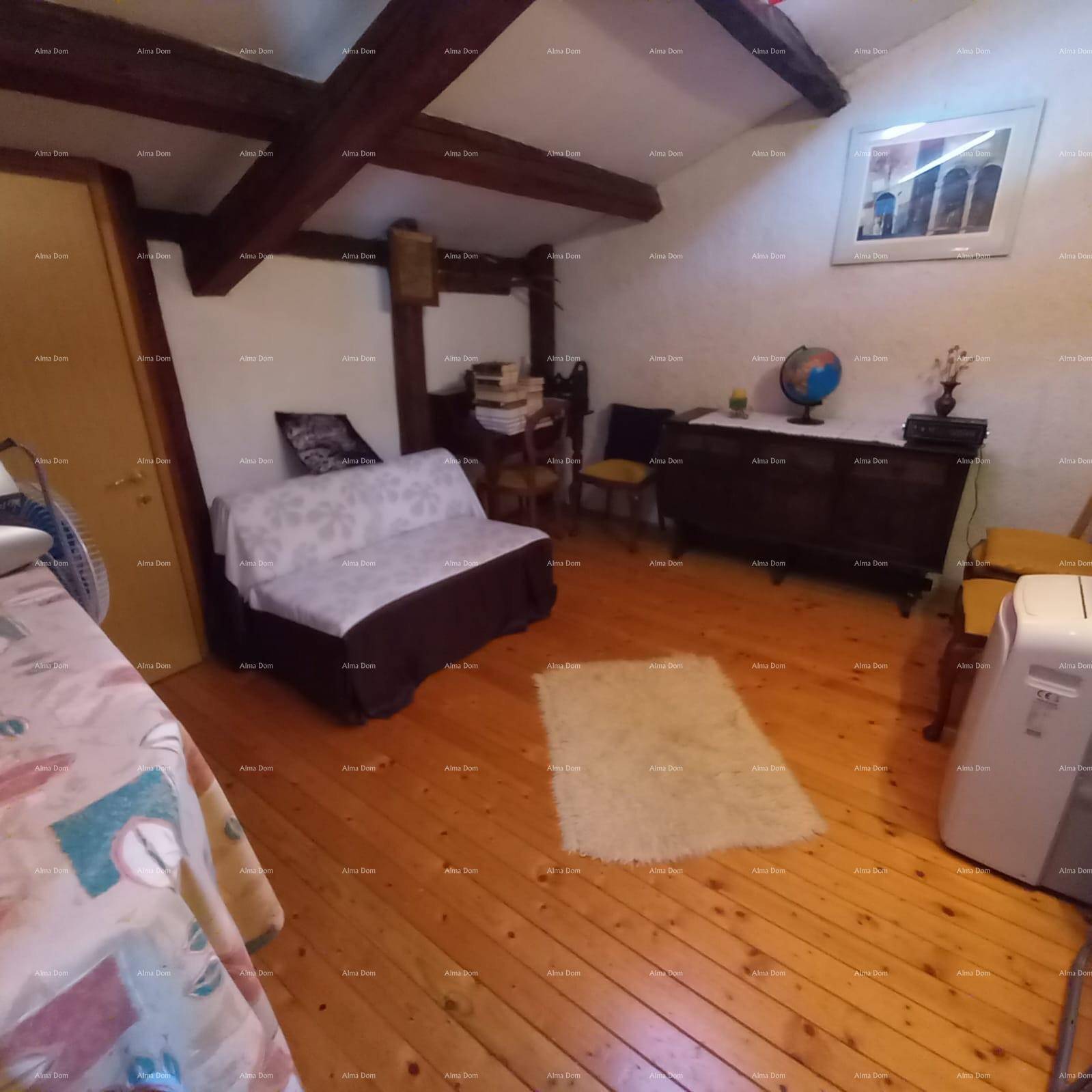 Schlafzimmer mit Holzboden, sichtbaren Deckenbalken und einem Teppich, der Gemütlichkeit verleiht.