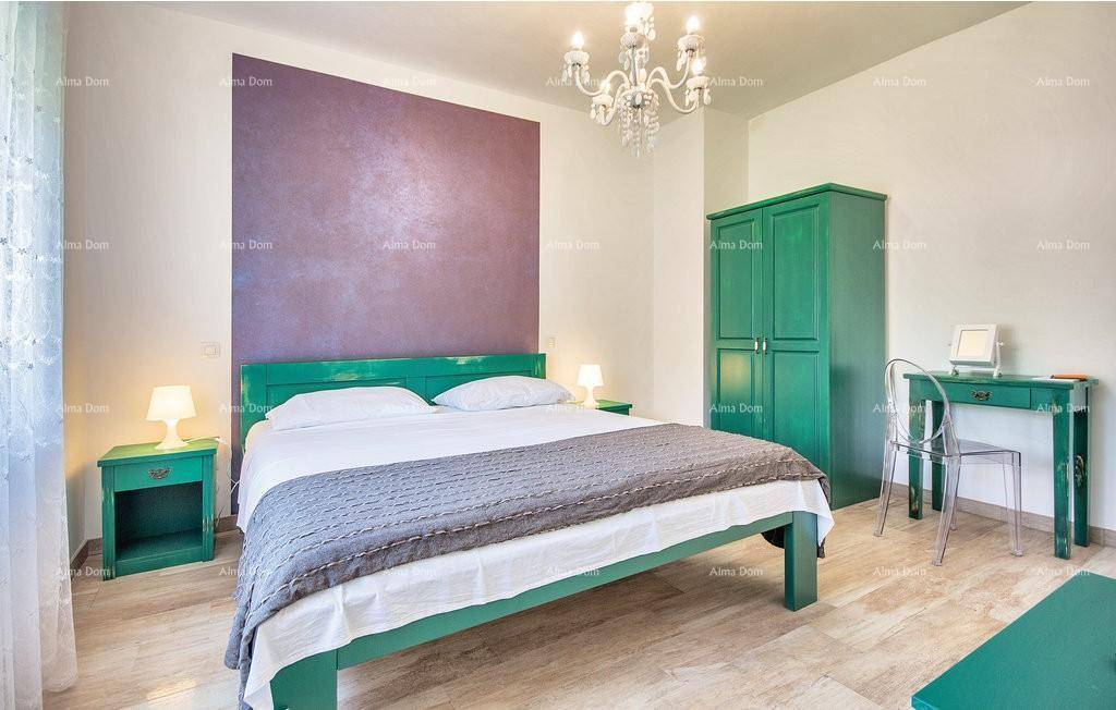 Schlafzimmer mit grünen Möbeln, violetter Akzentwand und elegantem Kronleuchter.