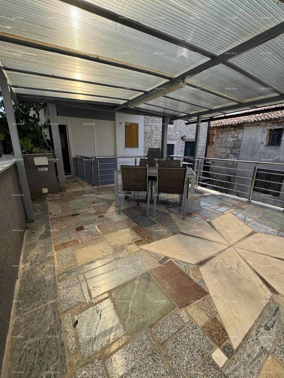 Geräumige, überdachte Terrasse mit Esstisch und Stühlen, gefliest mit Natursteinplatten.