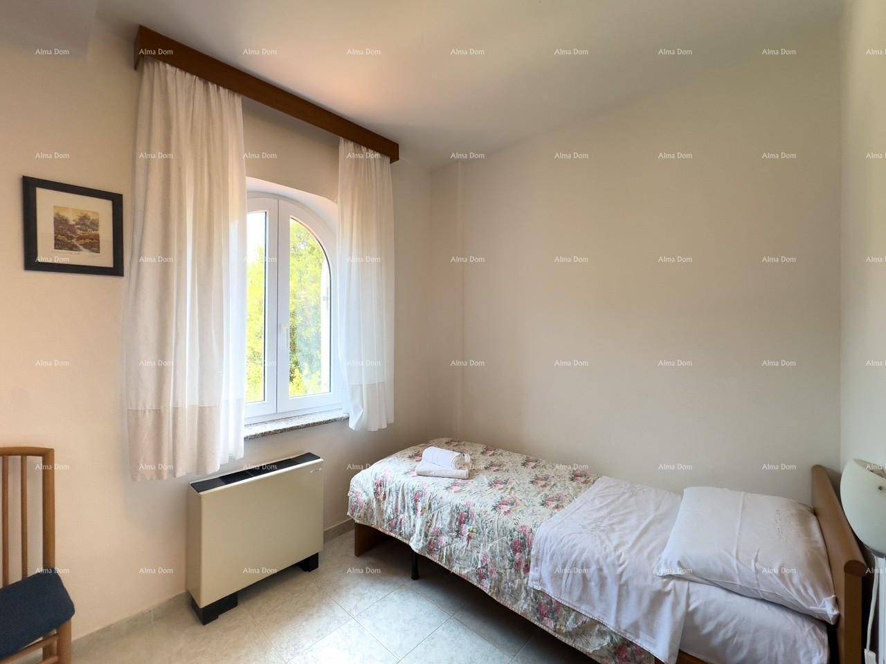 Helles Schlafzimmer mit Einzelbett, Fliesenboden und einem Fenster mit Blick ins Grüne.
