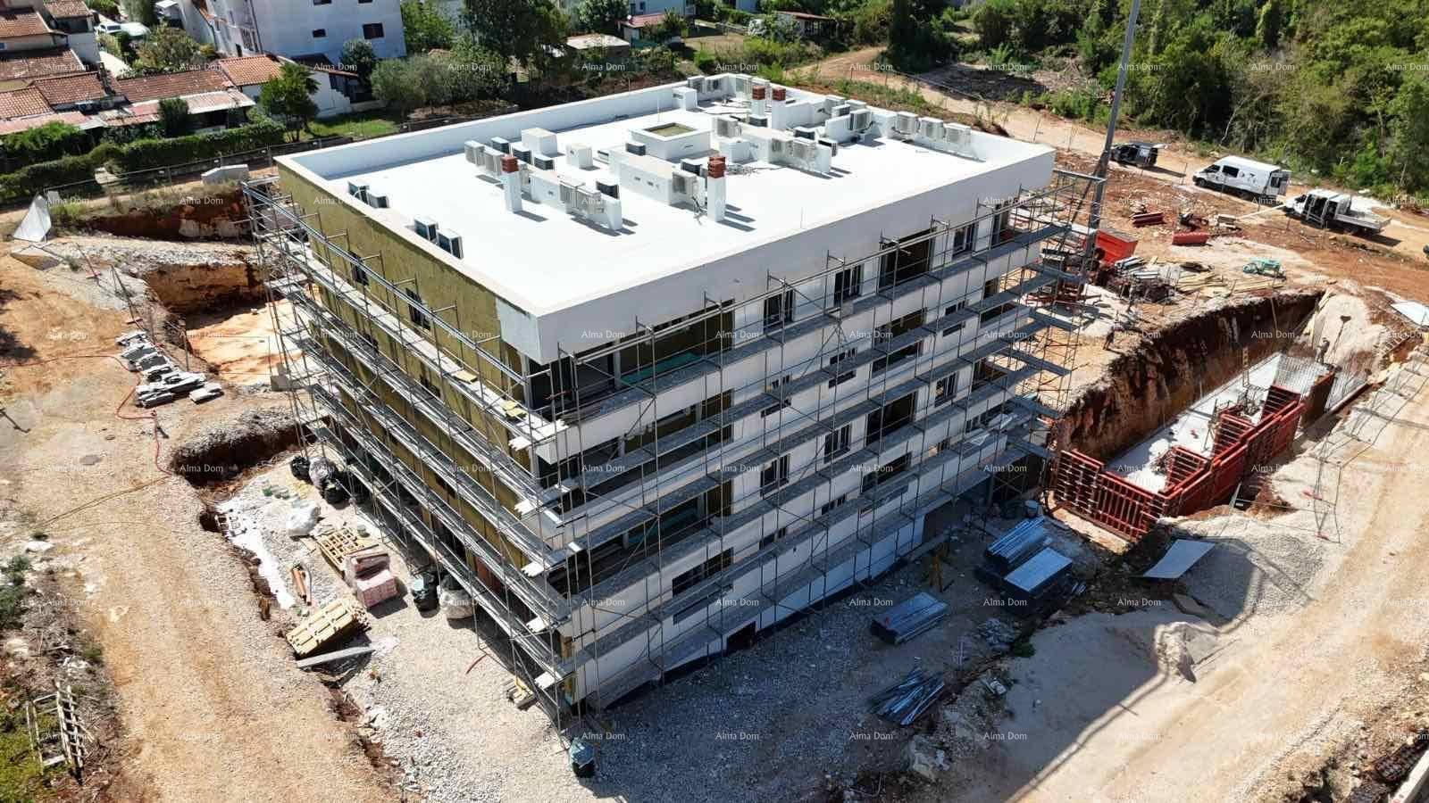 Baustelle eines Mehrfamilienhauses mit Gerüst und Dämmung an der Fassade, umgeben von Vegetation.