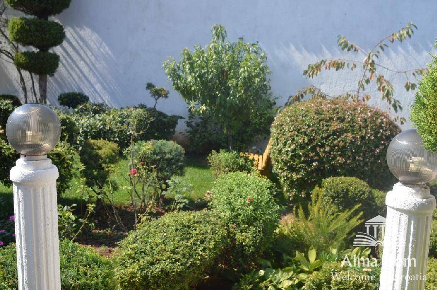 Gepflegter Garten mit vielfältigen Pflanzen und dekorativen Gartenleuchten.