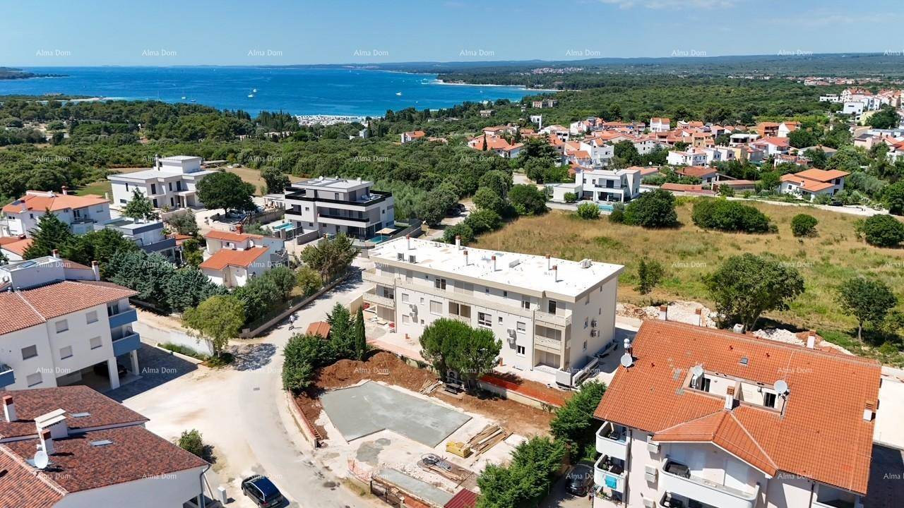 Panoramablick aus der Luft auf eine Wohnsiedlung mit Neubauten, umgeben von Natur und dem Meer.