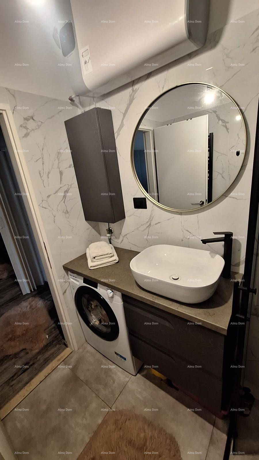 Badezimmer mit Waschbecken, Waschmaschine, rundem Spiegel und eleganten Marmorfliesen.