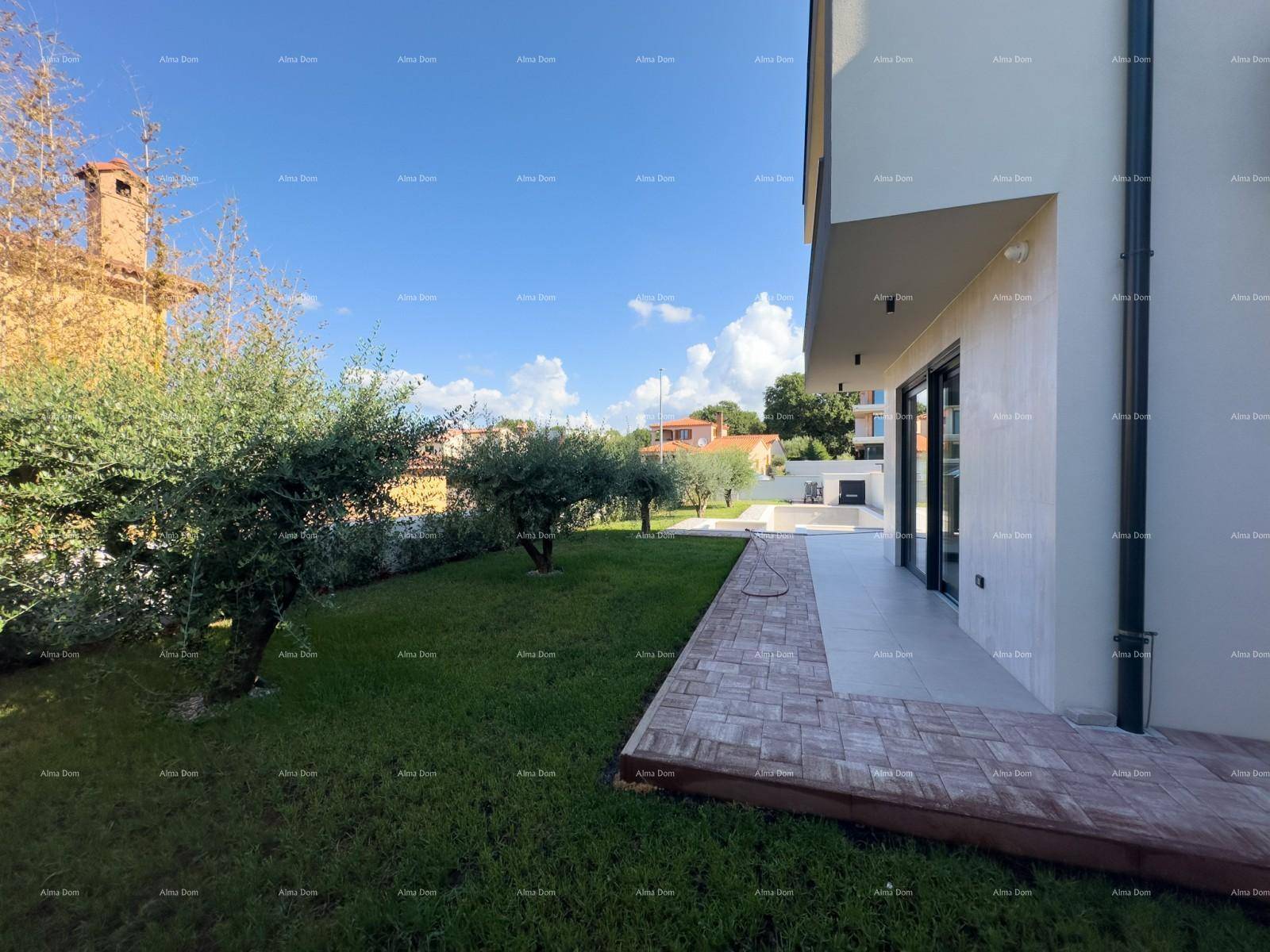 Seitenansicht der Villa mit Rasenfläche und einer kleinen gepflasterten Terrasse.