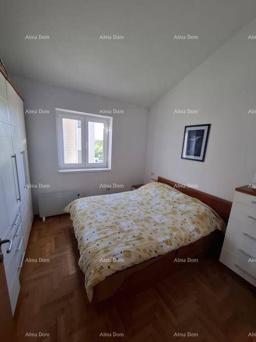 Schlafzimmer mit Holzboden, Doppelbett, weißem Kleiderschrank und Fenster mit Jalousien.