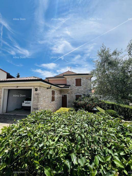 Ansicht des Hauses mit Steinfassade, integrierter Garage und einem gepflegten Vorgarten unter blauem Himmel.