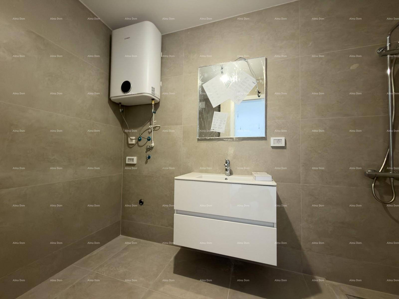 Modernes Badezimmer mit grauen Fliesen, schwebendem Waschtisch und Wandspiegel.