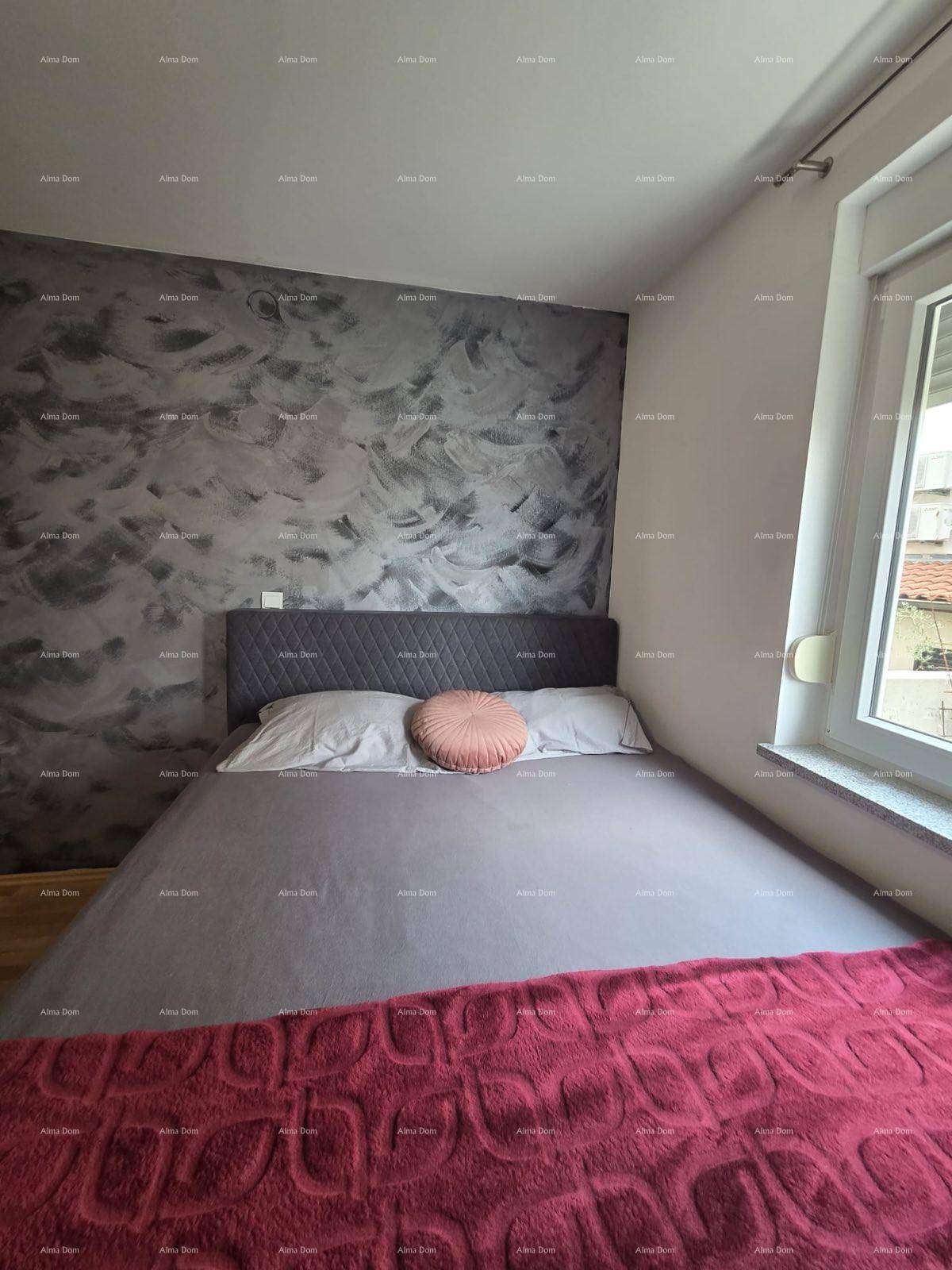 Schlafzimmer mit Doppelbett, strukturierter Akzentwand und Holzboden, hell durch ein Fenster.