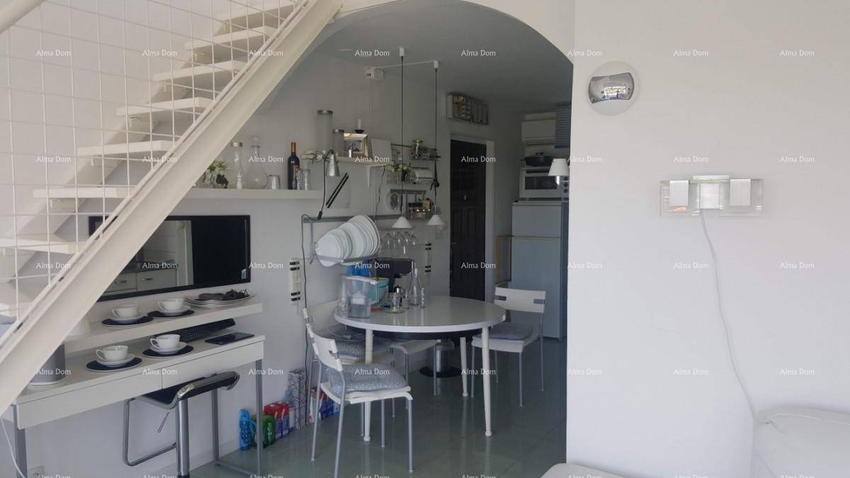Essbereich unter einer Treppe mit rundem Tisch, Stühlen und offener Küchenzeile im Hintergrund.