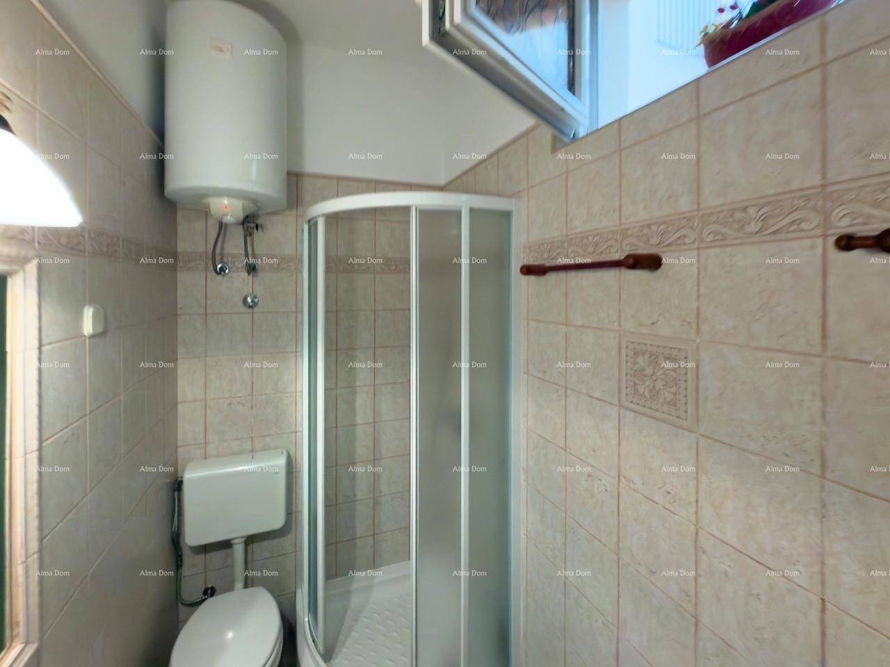 Badezimmer mit Dusche, Toilette und beigen Fliesen.