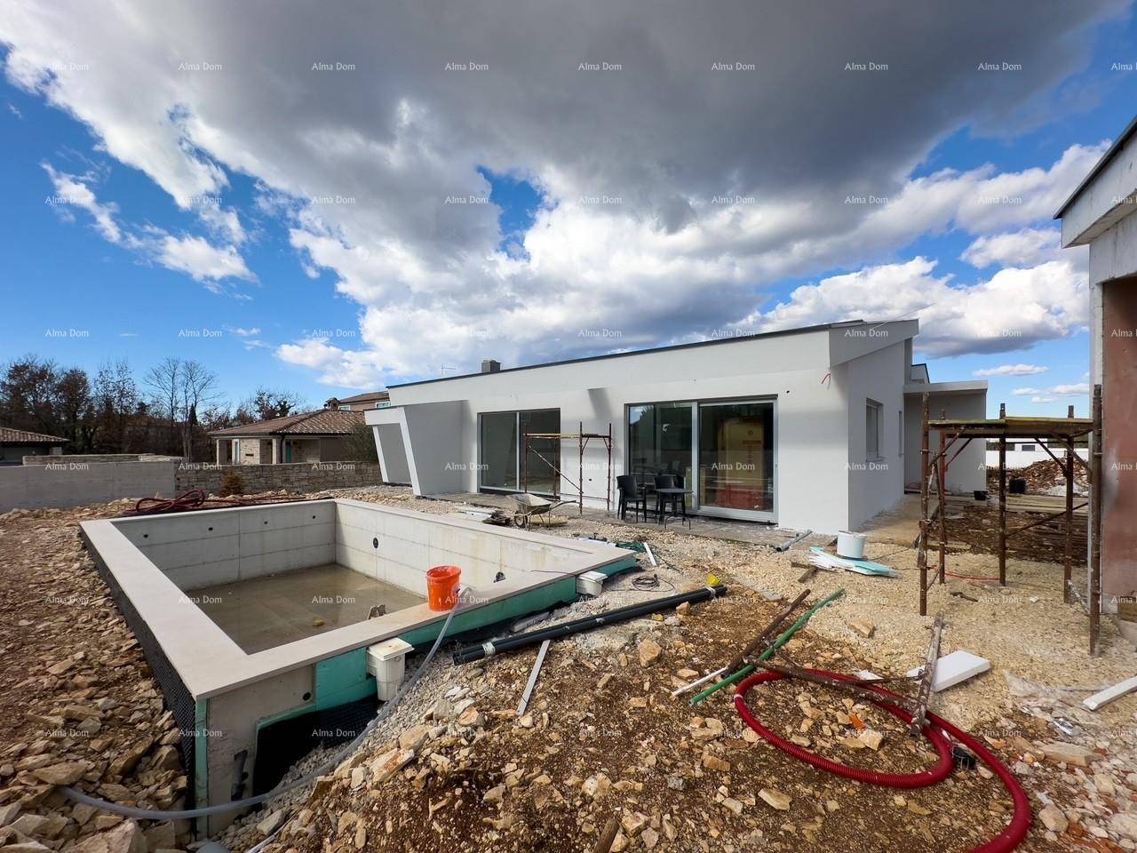 Moderner Neubau mit im Bau befindlichem Pool und Baustellenausrüstung im Vordergrund unter bewölktem Himmel.