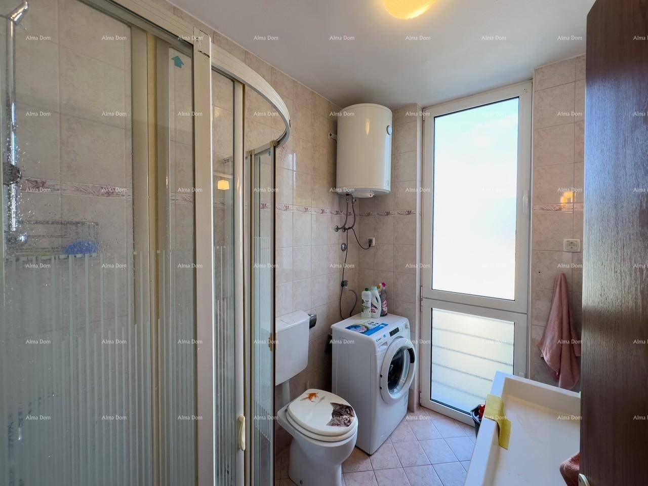 Badezimmer mit Duschkabine, Toilette, Waschmaschine und Fenster für natürliche Belüftung.