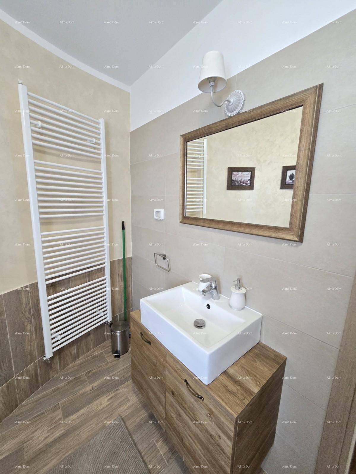 Badezimmer mit Einzelwaschbecken, Holzunterschrank, Spiegel und beheiztem Handtuchhalter.
