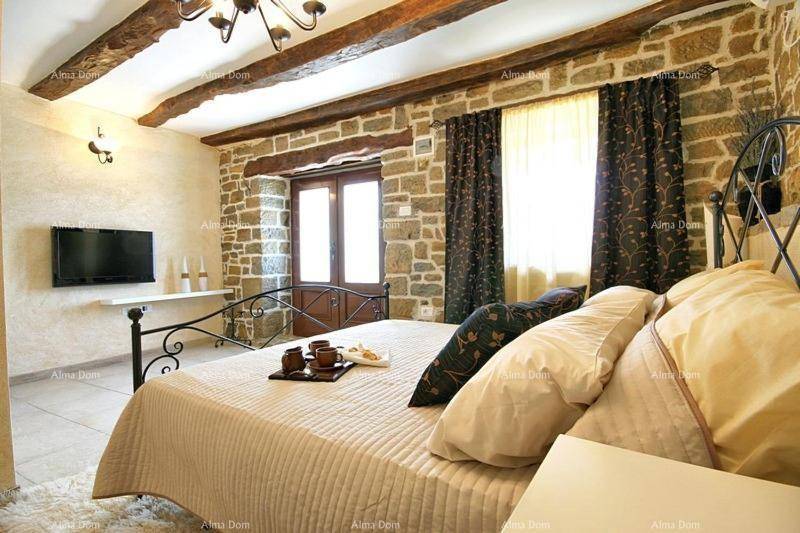 Rustikales Schlafzimmer mit Steinwänden, Holzbalken und schmiedeeisernem Bett.