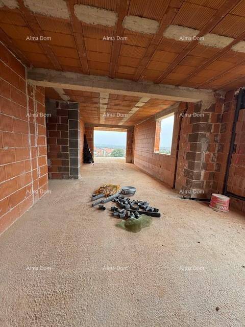 Unfertiger Innenraum mit Ziegelwänden, Baumaterialien und einer breiten Öffnung nach außen.