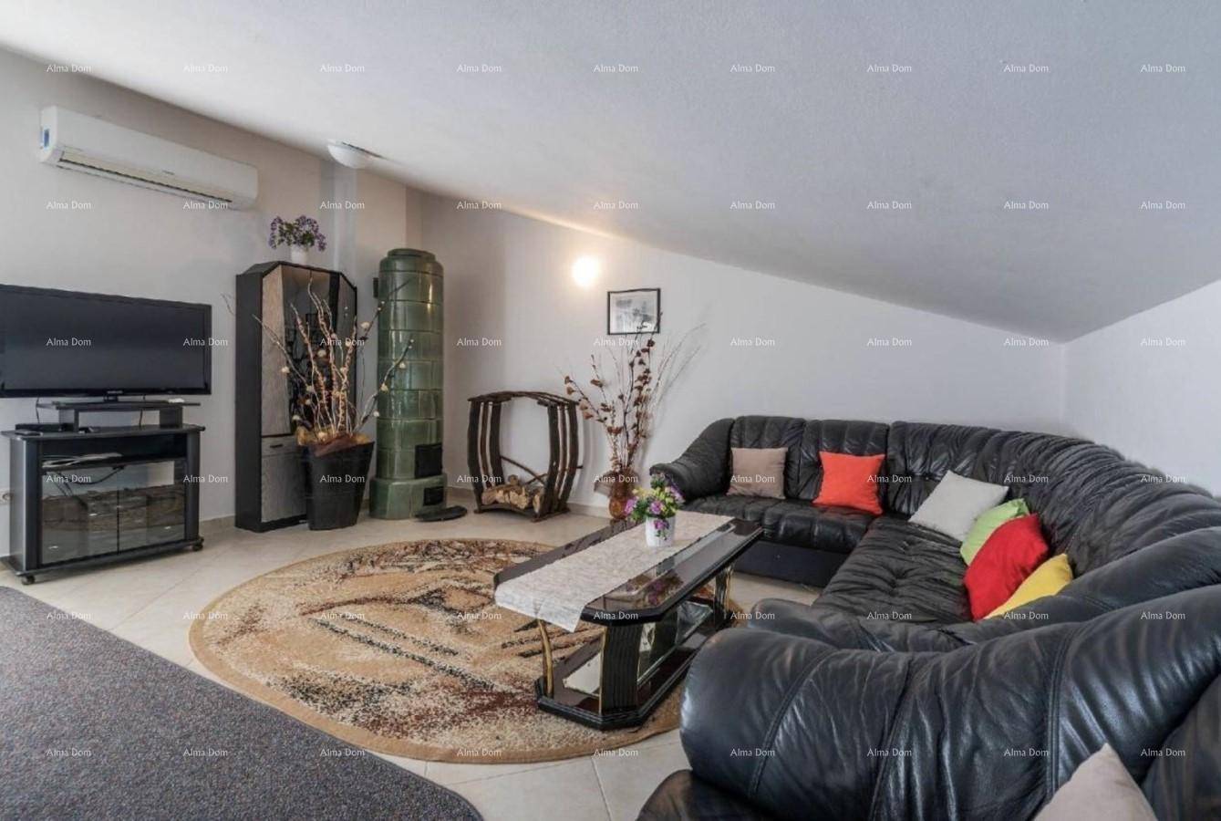 Gemütliches Wohnzimmer im Dachgeschoss mit Ledersofa, Teppich und Kachelofen.