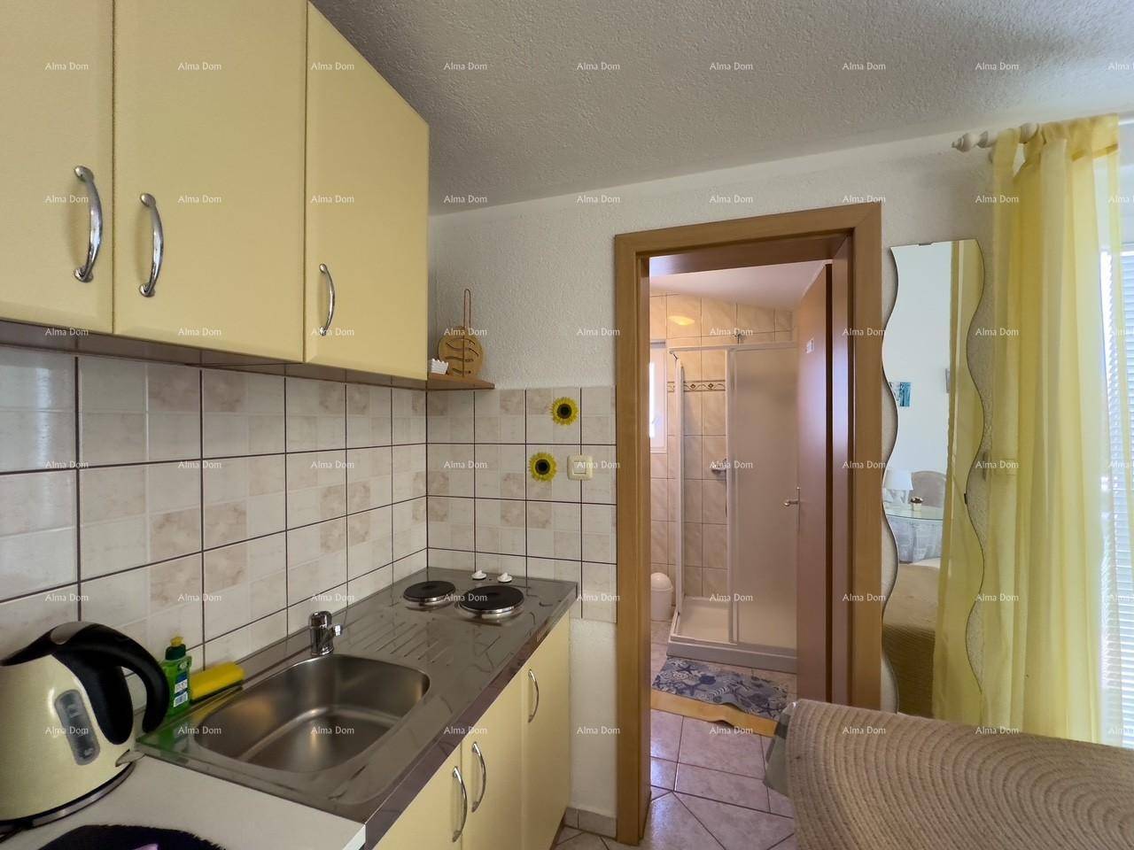 Funktionale Küchenzeile mit hellen Schränken und Fliesenrückwand, neben dem Badezimmerzugang.