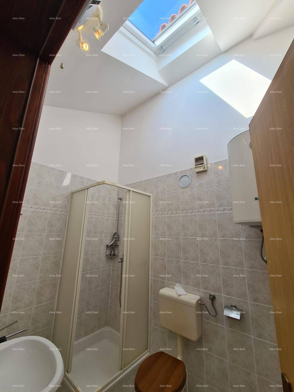 Badezimmer mit Fliesen, Duschkabine, Toilette, Waschbecken und einem Dachfenster für natürliches Licht.