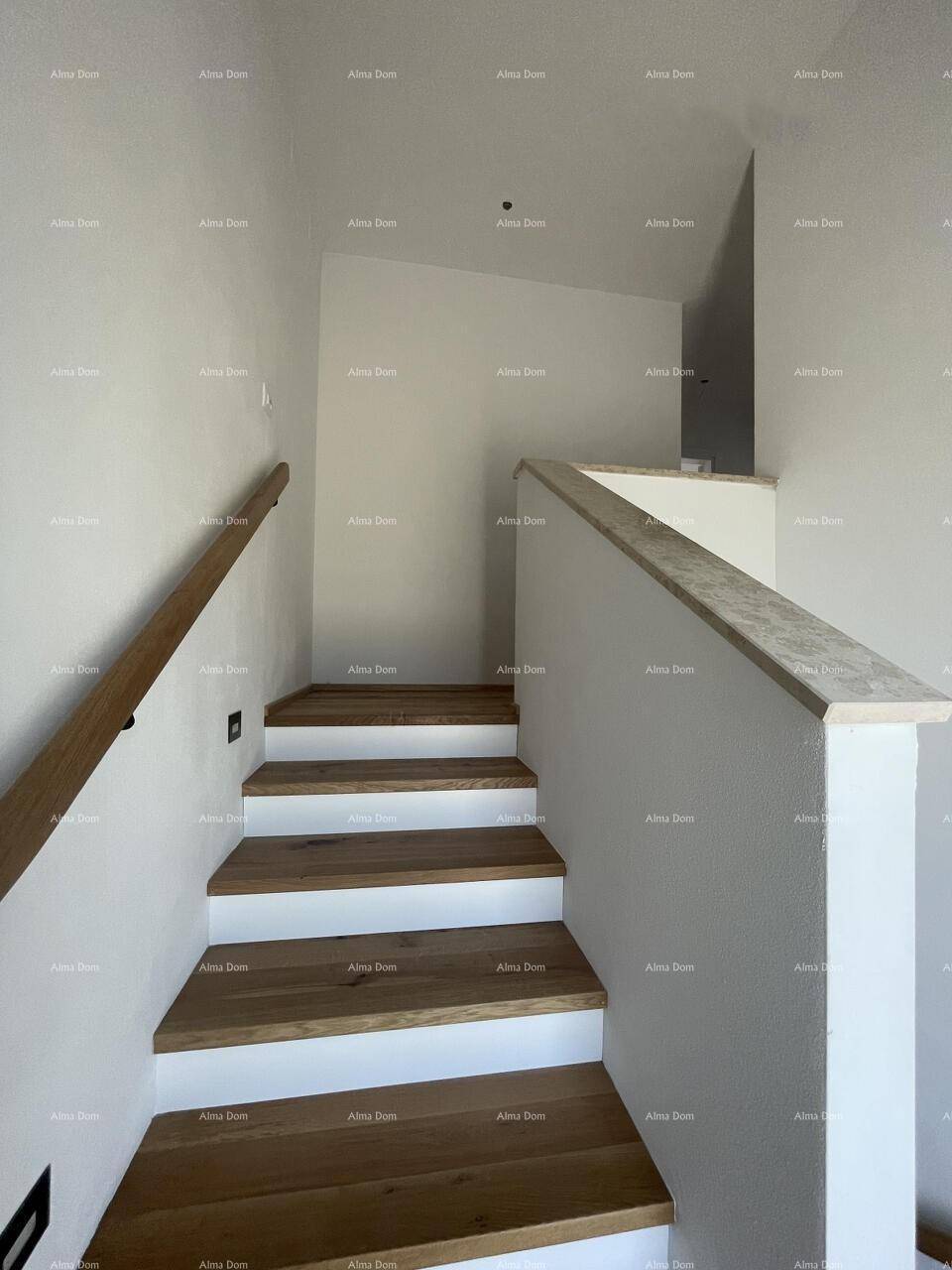 Elegante Holztreppe mit weißem Geländer, die die oberen Etagen des Hauses verbindet.