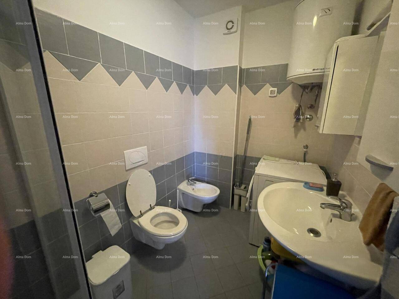 Praktisches Badezimmer mit Duschkabine, WC, Bidet und Waschbecken, ausgestattet mit Waschmaschine und Boiler.