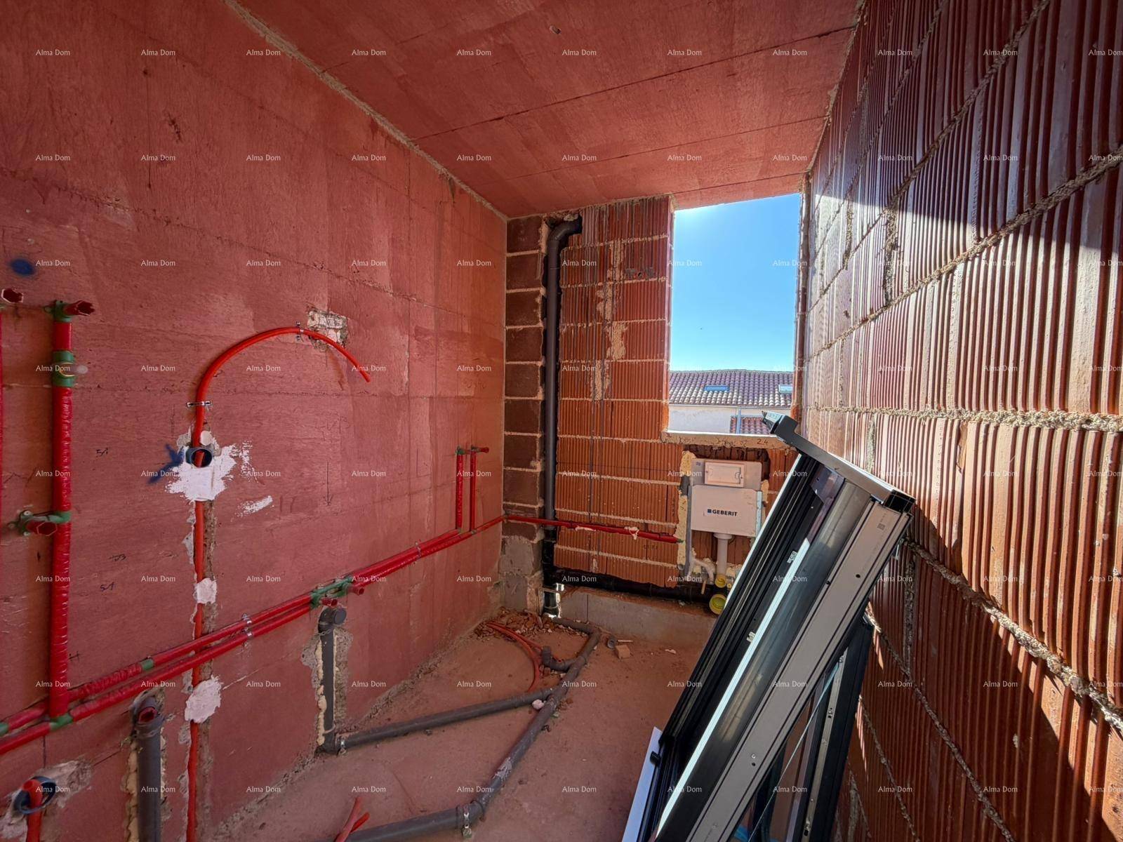 Badezimmer im Rohbau mit sichtbaren Wasserleitungen und einem Fenster für Tageslicht.