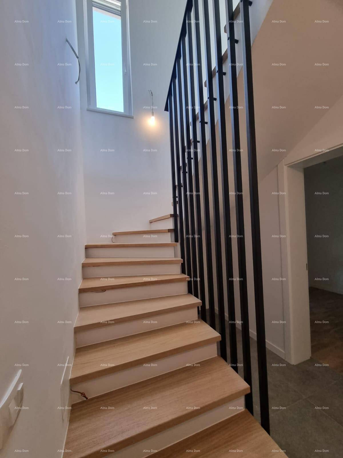 Moderne Holztreppe mit schwarzem Metallgeländer, die zu den oberen Etagen führt und viel Licht erhält.