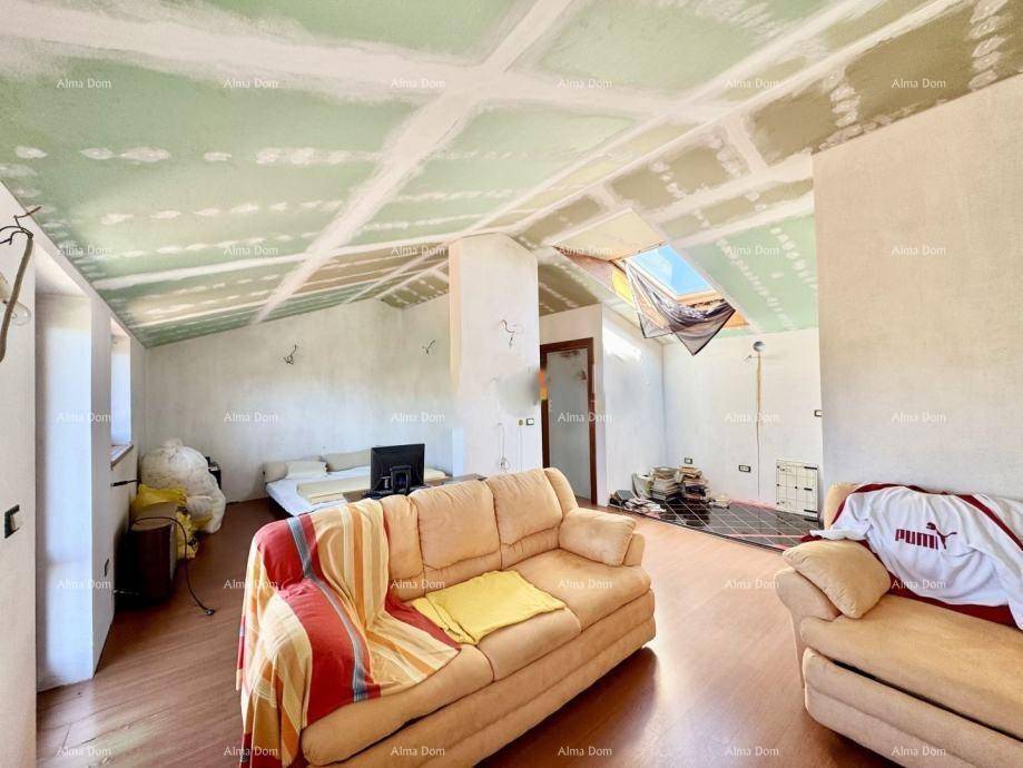 Unausgebauter Dachbodenbereich mit schrägen Wänden und Dachfenster, bereit für den Ausbau.