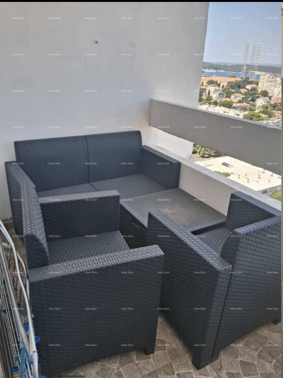 Möblierter Balkon mit Rattan-Sitzgruppe und weitem Blick über die Stadt.