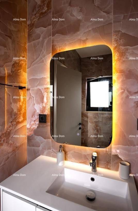Modernes Badezimmer mit beleuchtetem Spiegel, Waschtisch und auffälligen Marmorfliesen.