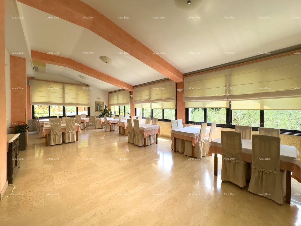 Geräumiger Speisesaal mit vielen Tischen und Stühlen, großen Fenstern und hellem Steinboden.
