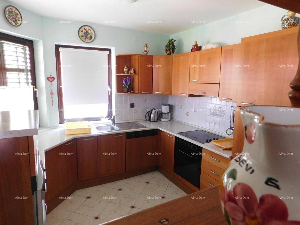 Funktionale Küche mit Holzschränken, weißen Fliesen und einem Fenster für Tageslicht.