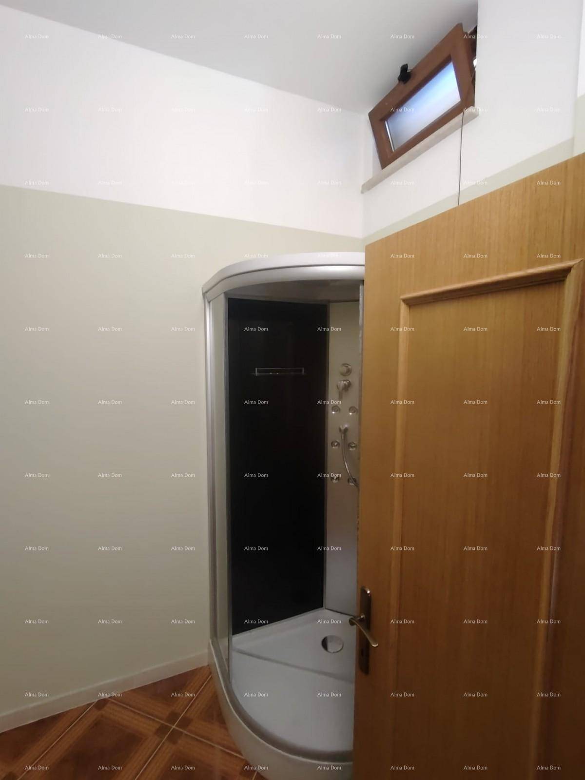 Badezimmer mit Duschkabine, gemustertem Fliesenboden und einem kleinen Fenster für Belüftung.