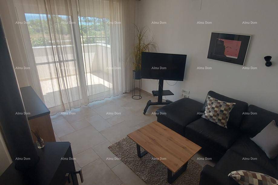 Gemütliches Wohnzimmer mit dunklem Sofa, Couchtisch und großen Fenstertüren, die viel Tageslicht hereinlassen.