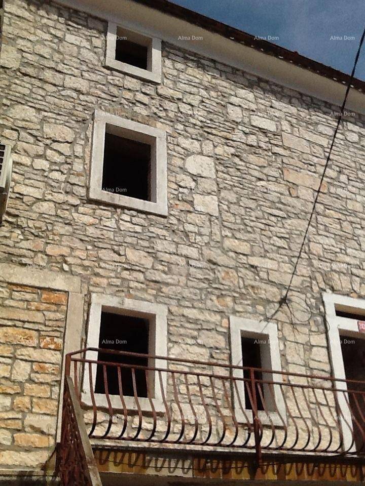 Traditionelle Steinfassade eines Gebäudes mit kleinen Fenstern und einem Balkon mit Eisengeländer.