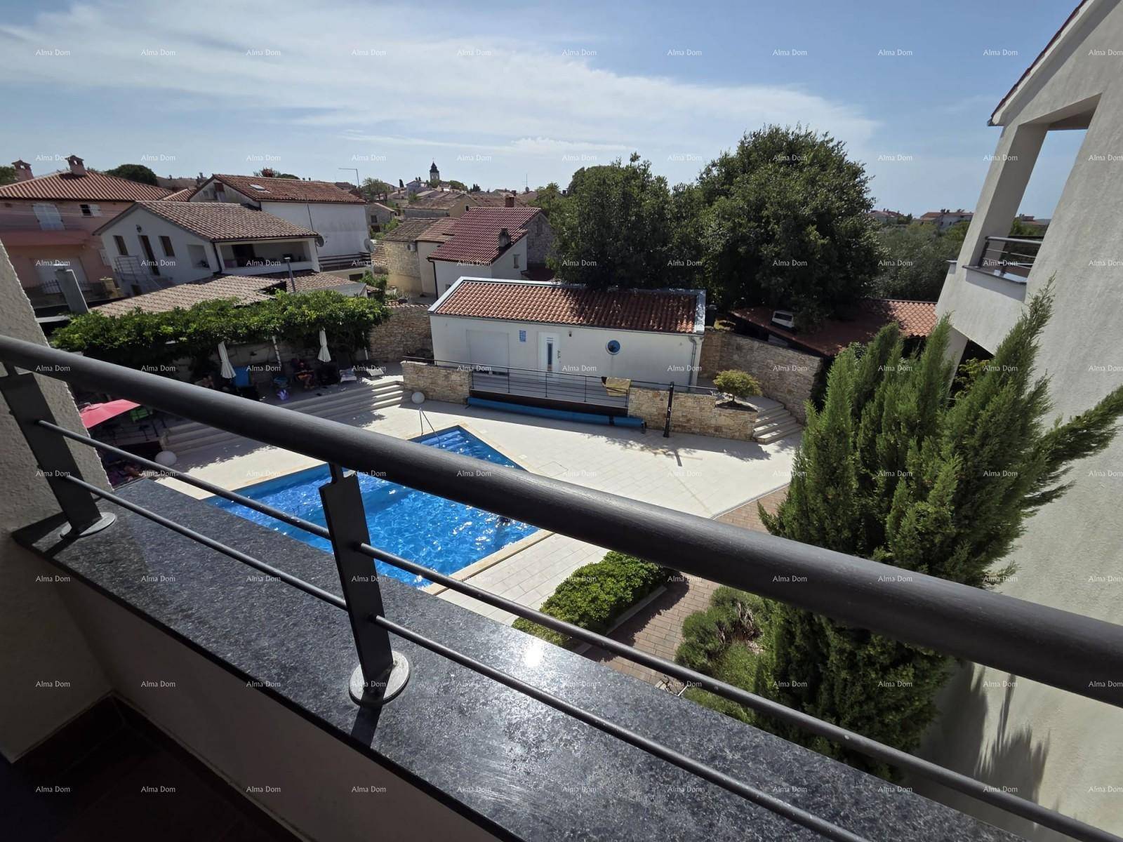 Blick vom Balkon auf den Swimmingpool und die umliegende Wohngegend unter blauem Himmel.
