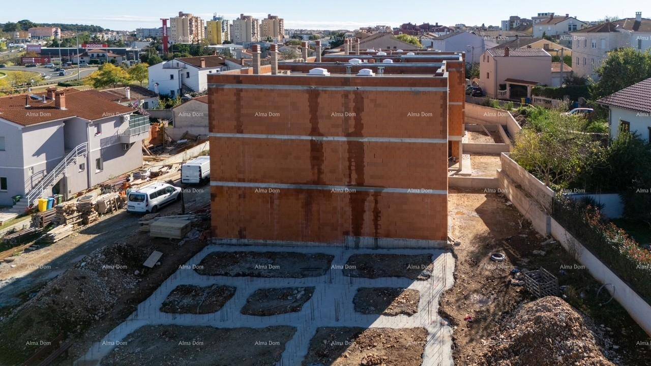 Rückseite des im Bau befindlichen Gebäudes mit sichtbaren Ziegelwänden und Fundamentarbeiten.
