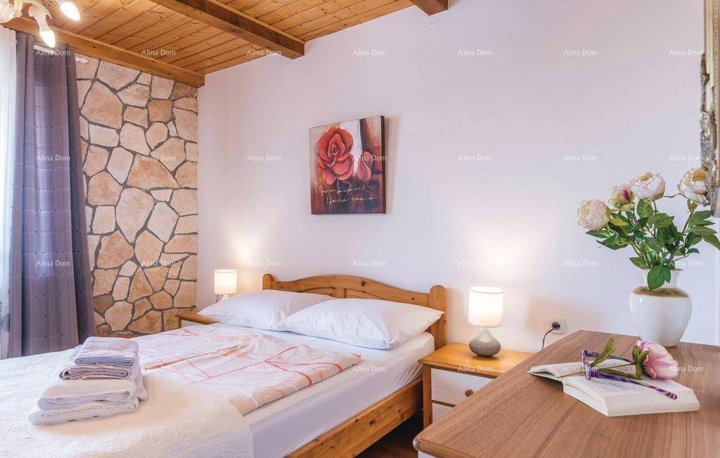 Helles Schlafzimmer mit Holzbalkendecke, Doppelbett und dekorativer Steinwand.