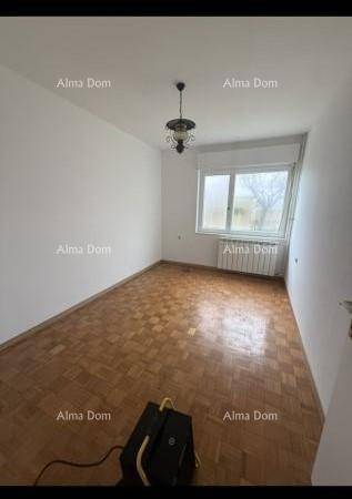 Helles Schlafzimmer mit Parkettboden, weißen Wänden und Fenster mit Heizkörper darunter.