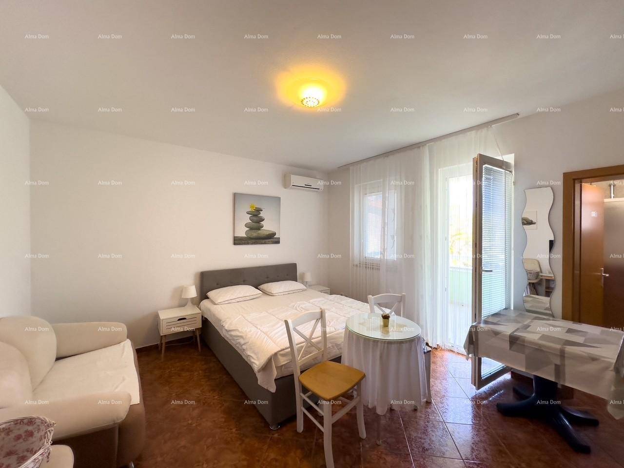 Helles Schlafzimmer mit Doppelbett, kleiner Sitzecke und direktem Zugang zum Balkon.