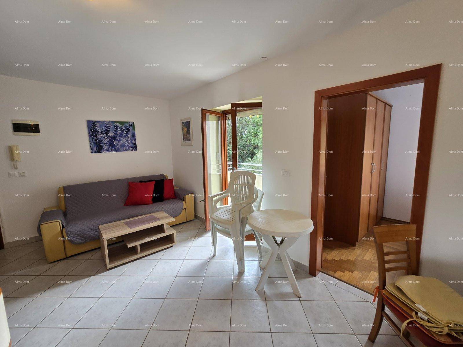 Wohnzimmer mit Sofa, kleinem Tisch und Zugang zum Balkon, daneben ein weiterer Raum.