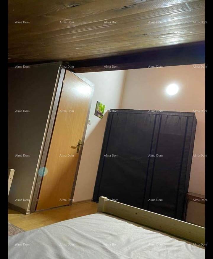 Schlafzimmer mit Holzbalkendecke, Bett, Holztür und Kleiderschrank.
